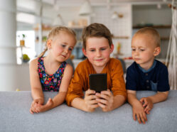 ilustrační foto: Děti koukají na mobilní telefon.